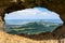 Stunning view through a rock window at the summit of famous Pali Puka hiking trail on the island of Oahu, Hawaii, USA. The dangero