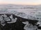 Stunning view of uncountable icebergs on the black sand beach under the sunset sky