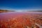 Stunning view of a vast body of pink-hued water, encircled by rugged rocky landscape