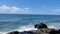 Stunning view of the waves crashing on the rocks by the sea under the blue sky in a sunny day climate.