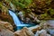 Stunning waterfall into boulders surrounded by forest and cliffs