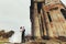 Stunning wedding couple stands in the cold weather behind a cathedral