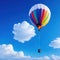 A stunning white hotr balloon with rainbow colors floating on a blue