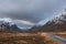 Stunning Winter landscape image of snowcapped Three Sisters mountain range in Glencoe Scottish Highands with dramatic sky