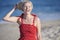 Stunning young blonde woman poses at beach in red sundress