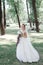 Stunning young bride in white dress holding bouquet in park