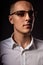 Style elegant young business man in eye glasses looking sreious and arrogant on dark shadow background. Closeup