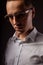 Style elegant young business man in eye glasses looking sreious and arrogant on dark shadow background. Closeup