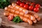 Styled Grilled Frankfurter sausages on wooden board with tomatoes and green herbs