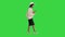 Stylish african american woman in knitwear and hat using her phone while walking on a Green Screen, Chroma Key.