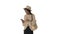 Stylish african american woman in knitwear and hat using her phone while walking on white background.