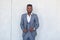 Stylish African black man is posing in three piece suit against a gray concrete wall