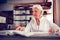 Stylish aged lady with facial wrinkles sitting at table and reading book