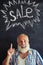 Stylish aged man against chalk advertisement of sale written on