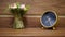 Stylish alarm clock and a small bouquet of artificial flowers on the bedside table