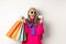 Stylish asian grandmother in sunglasses going shopping on holiday sale, holding paper bags and plastic credit card
