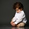 Stylish baby boy sitting on floor interested with his feet portrait