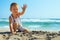 Stylish baby boy waving hand on the beach