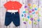 Stylish baby clothes and colorful letters on a gray wooden background. View from above. The concept of knowledge of the world and