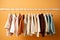 stylish baby clothes hanging on rack against color background