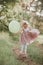 Stylish baby girl holding big balloon wearing trendy pink dress in meadow. Playful. Birthday party