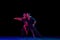 Stylish ballroom dancers couple in gorgeous outfits dancing in sensual pose on dark background in neon light. Concept of