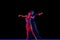 Stylish ballroom dancers couple in gorgeous outfits dancing in sensual pose on dark background in neon light. Concept of