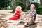 Stylish beaming pensioners drinking red wine while having picnic