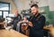 Stylish bearded barman dressed black uniform smiling at camera, beer tapping at bar counter and waiter with tray. Successful