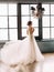 Stylish, beautiful bride in a luxurious dress posing against the backdrop of a rich interior. Fine Art Wedding