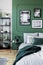 Stylish bedroom interior with double bed and emerald green wall