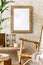 Stylish and beige composition of home interior with rattan armchair, mock up picture frame, wooden bench, decoration, plant.