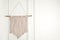 Stylish beige macrame hanging on white wall. Space for text