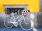 Stylish bicycle with a basket full of flowers leaning against a yellow wall in the streets of Porto, Portugal