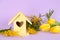 Stylish bird house and fresh flowers on violet background