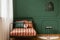 Stylish black chandelier above industrial black metal table with book in dark green teenager bedroom