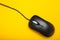 Stylish black optical computer mouse isolated on a yellow background. View from above