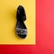 Stylish black-silver sandal decorated with a scattering of rhinestones on yellow and red background. Fashion blog. shoe sale