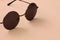 Stylish black sunglasses with round glasses lies on a blanket made of soft and fluffy light orange fleece fabric. Fashionable