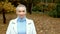 Stylish blond woman with very short hair in a white leather jacket, walking in the autumn Park. looking at the camera