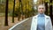 Stylish blond woman with very short hair in a white leather jacket, walking in the autumn park. Looking at the camera