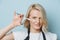 Stylish blonde female hairdresser holding open scissors next to her face