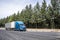 Stylish blue big rig long haul industrial semi truck transporting cargo in dry van semi trailer running on the highway road with