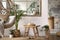 The stylish boho composition with changing swing, stool, window and plants. Beige carpet with slippers. White wall. Template