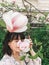 Stylish boho girl making selfie with beautiful pink magnolia flowers on branch. Hipster girl smelling and posing with magnolia