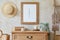 Stylish boho interior of living room with brown mock up poster frame, elegant accessories, flowers, ladder, wooden shelf.