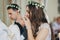 Stylish bride and groom in floral crowns drinking holy eucharist during matrimony in church. Wedding ceremony in cathedral.