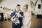 Stylish bride and groom hugging and having fun with pug dog in bow tie at wedding reception. Happy wedding couple with their dog