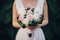Stylish bride in silk dress holding unusual wedding bouquet close up in summer park. Bridal wedding bouquet composition of green