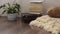 Stylish brightly part of living room with old vintage suitcase, books, potted plant and woolen handmade blanket on luxury wooden f